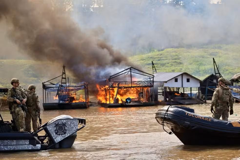 Agentes da Polícia Federal ao lado de dragas de garimpo ilegal em chamas em rio da Amazônia