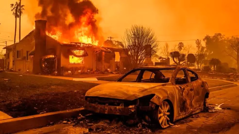 Incêndio florestal de grandes proporções com fumaça densa sobre área urbanizada